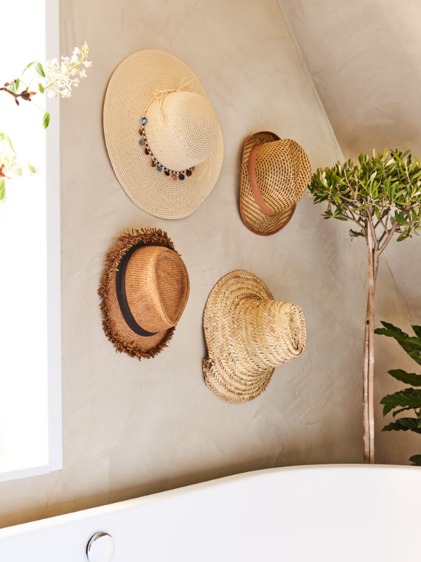 Leg je zomerhoeden niet in de kast maar hang ze op aan de badkamermuur voor een instant tropical vibe.
